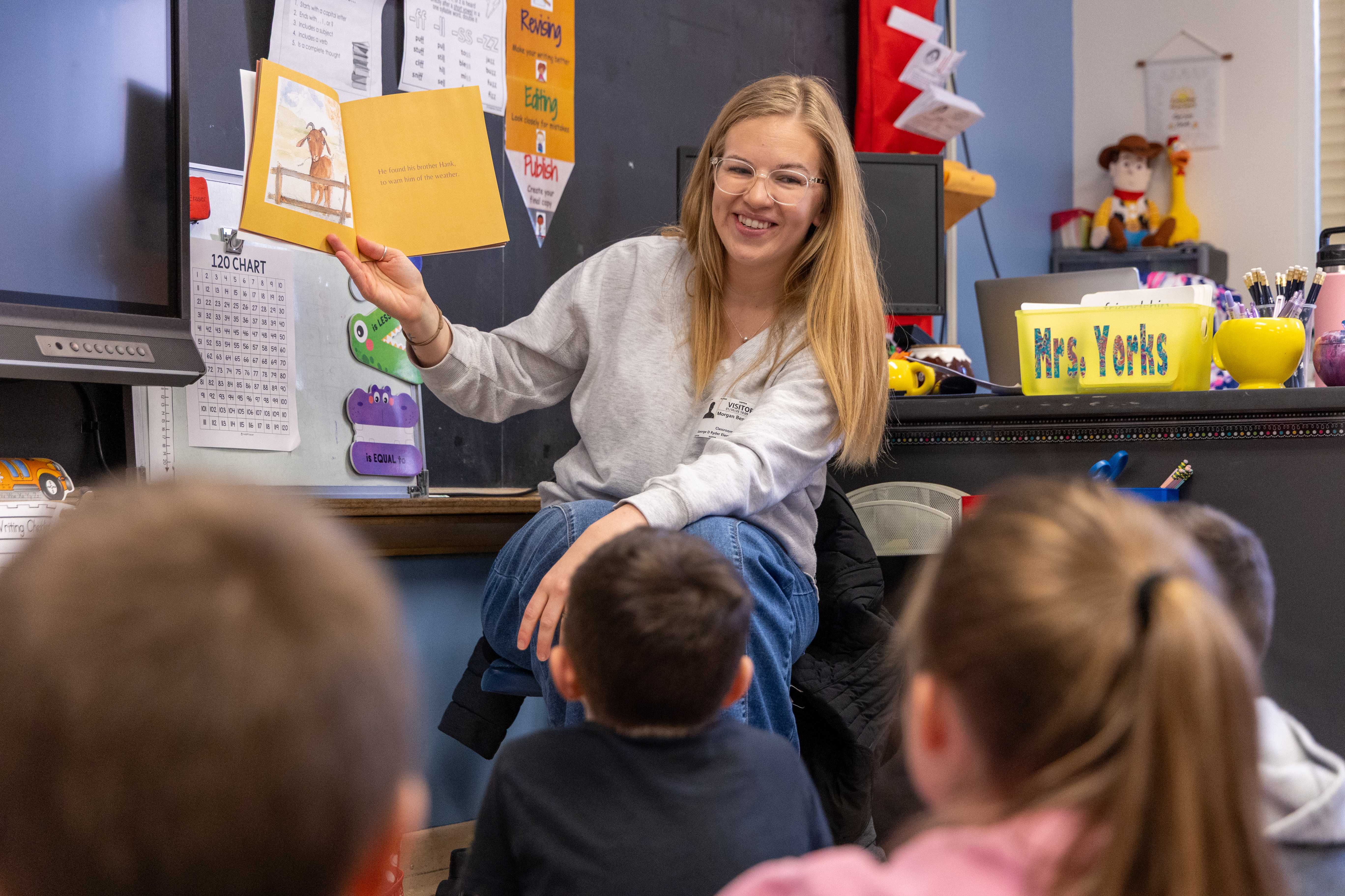 Benson smiles to the class while reading her book